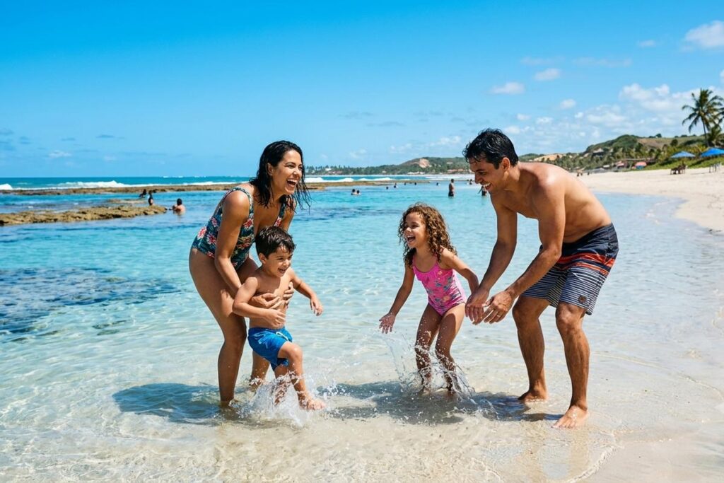 Família brasileira brincando na praia em um dos destinos no Brasil para viajar com crianças.