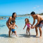 Família brasileira brincando na praia em um dos destinos no Brasil para viajar com crianças.