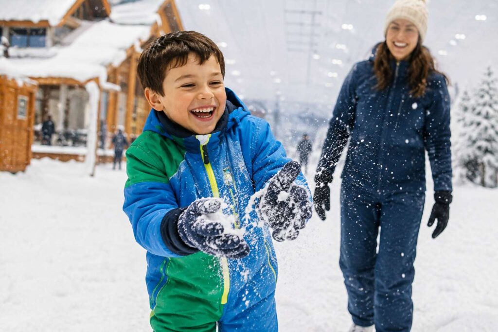 Menino brincando na neve artificial em Gramado com crianças durante passeio em família